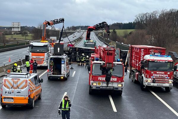 Rettungskräfte arbeiten an einem Unfall auf der Autobahn, mit mehreren Einsatzfahrzeugen und einem umgekippten Lkw.