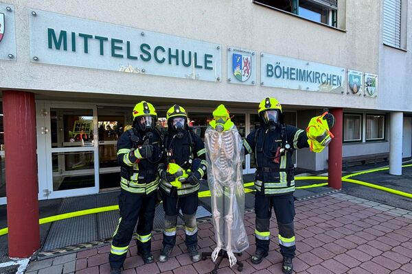 Feuerwehrleute posieren vor der Mittelschule Böheimkirchen mit einem künstlichen Skelett für ein Foto.